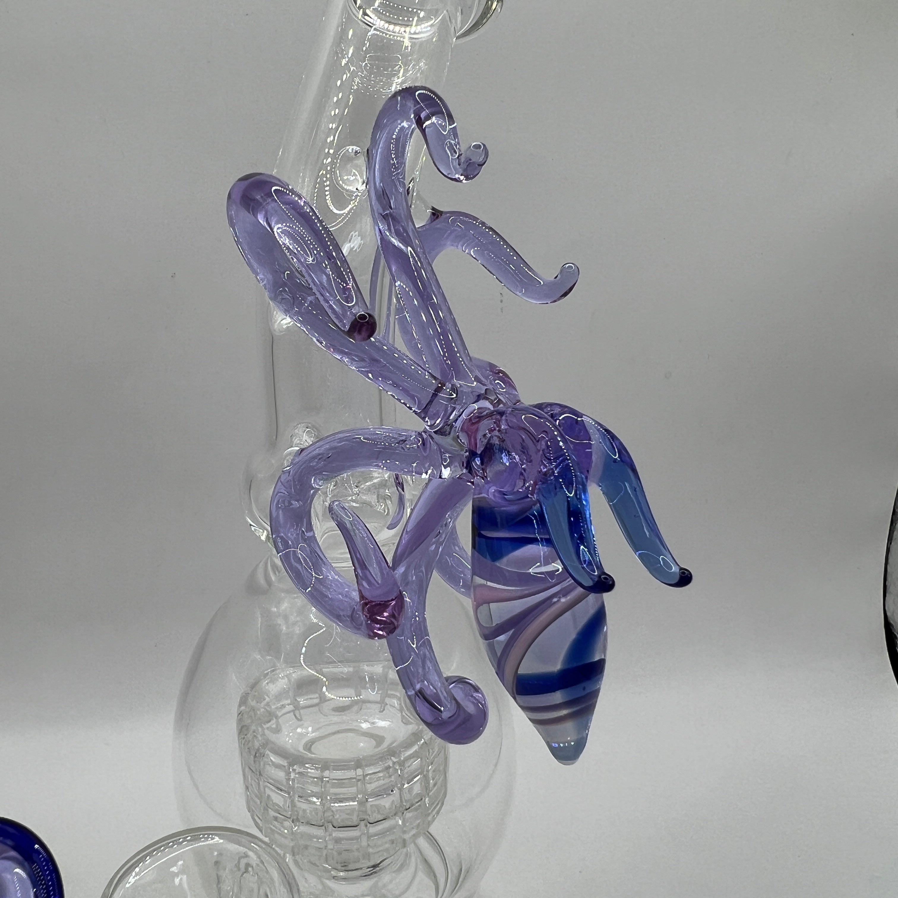Close up view of handcrafted OTG Glass squid sculpture with flowing tentacles and striped blue body